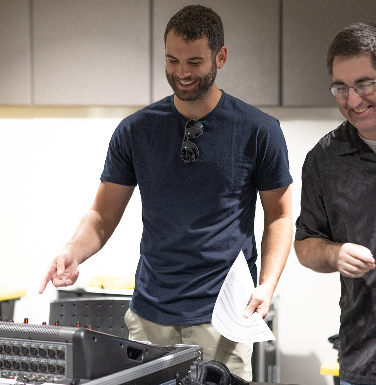 production volunteers smiling and pointing at audio mixer